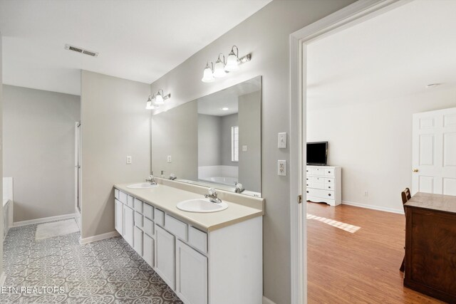 full bath with visible vents, baseboards, a garden tub, and a sink