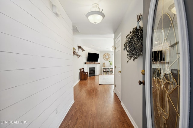 hall with visible vents, baseboards, and dark wood-style flooring