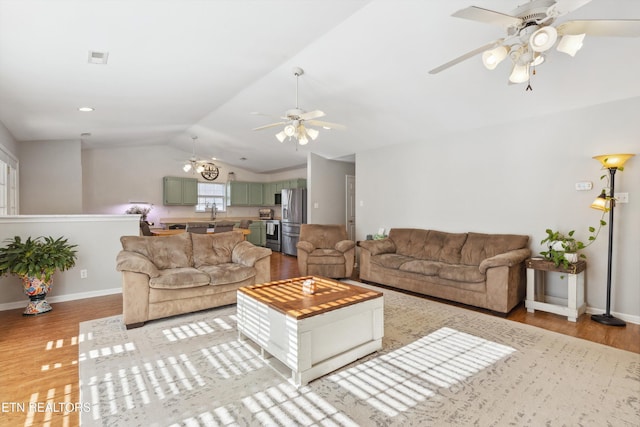 living room featuring visible vents, light wood-style flooring, baseboards, and lofted ceiling