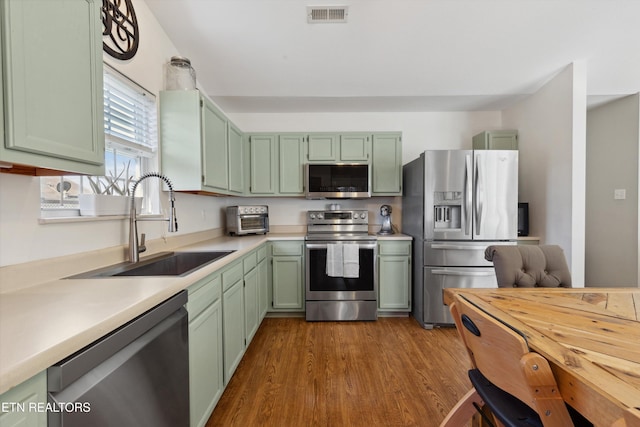 kitchen featuring visible vents, a sink, stainless steel appliances, light countertops, and green cabinetry