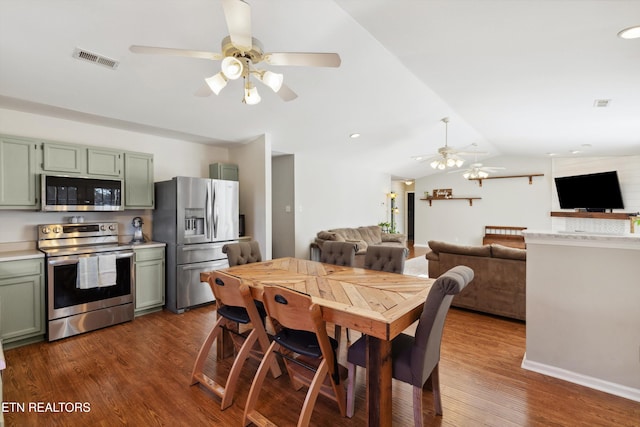 dining room with dark wood finished floors, vaulted ceiling, a ceiling fan, and visible vents