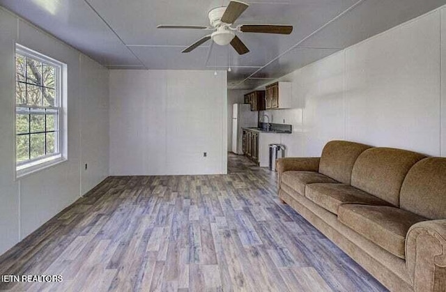 unfurnished living room featuring ceiling fan, a sink, and wood finished floors