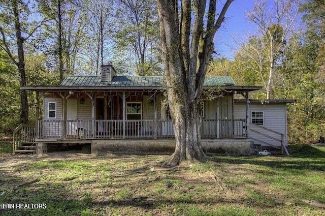 view of front of house with metal roof, a porch, and a front yard