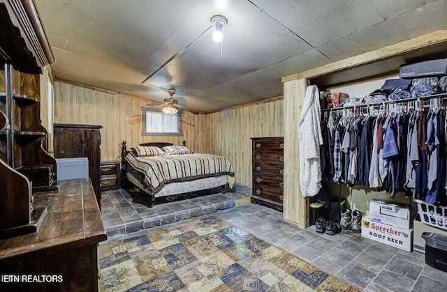 bedroom with stone finish floor, a closet, and wood walls