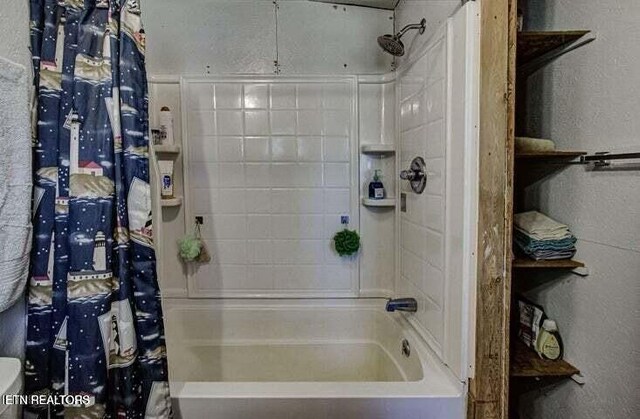 bathroom featuring a textured wall and shower / bath combo with shower curtain