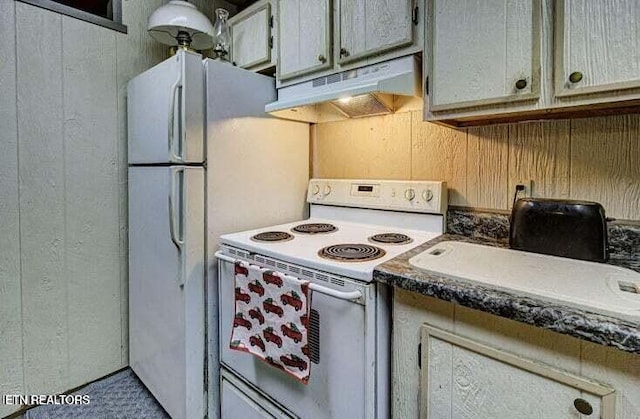 kitchen with electric stove, wood walls, dark countertops, and under cabinet range hood