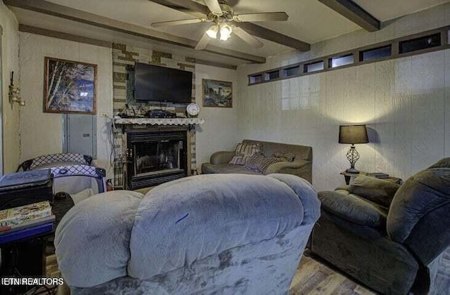 living area featuring wood finished floors, a fireplace, beamed ceiling, and ceiling fan