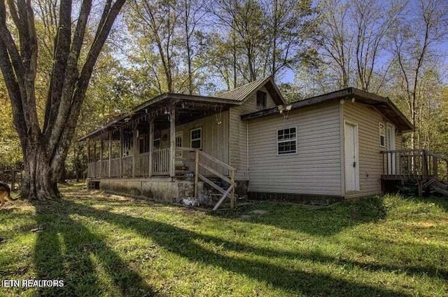 view of front facade with a front yard, covered porch, and metal roof