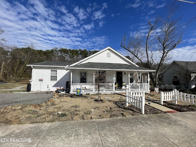 view of front of property with fence, a porch, and a shingled roof