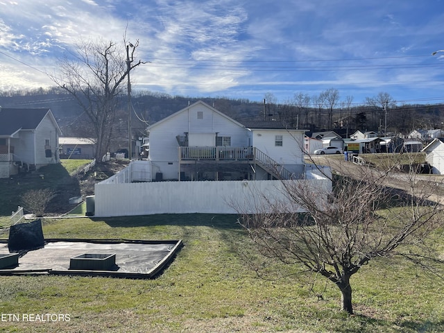 back of property with a lawn and fence