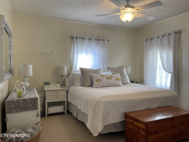 bedroom featuring light colored carpet, ornamental molding, a ceiling fan, and a textured ceiling