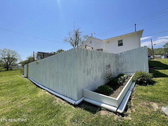 view of side of property featuring fence and a yard