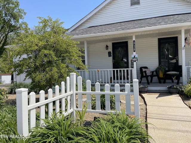view of exterior entry with a porch and fence