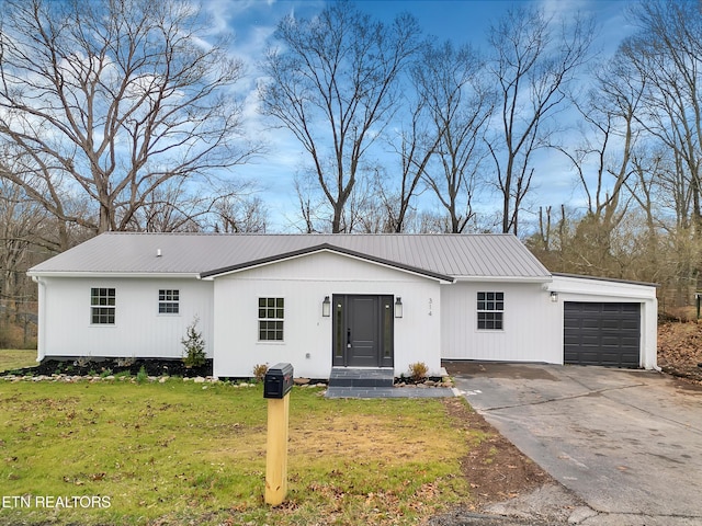 view of front of home with a garage, metal roof, a front lawn, and concrete driveway