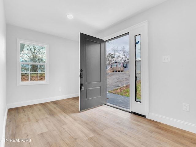 foyer entrance with light wood finished floors and baseboards