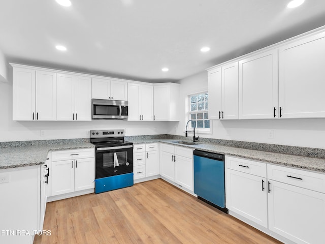 kitchen featuring stainless steel appliances, light wood-style floors, white cabinetry, a sink, and recessed lighting