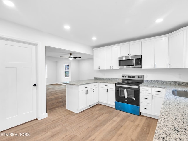 kitchen featuring a peninsula, light wood finished floors, white cabinetry, and stainless steel appliances