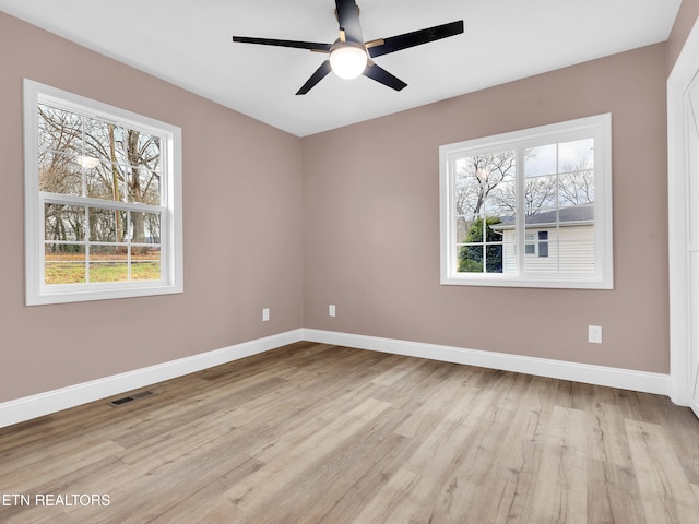 spare room featuring light wood-type flooring, visible vents, and baseboards