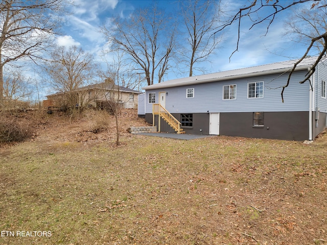 back of property featuring stairway, metal roof, a lawn, and a patio