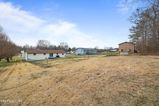 view of yard with a storage unit, fence, and an outbuilding