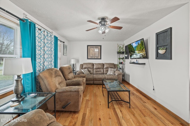 living area with light wood finished floors, a ceiling fan, and a textured ceiling