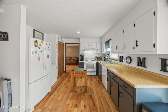 kitchen with white appliances, white cabinets, light wood-style flooring, light countertops, and a sink