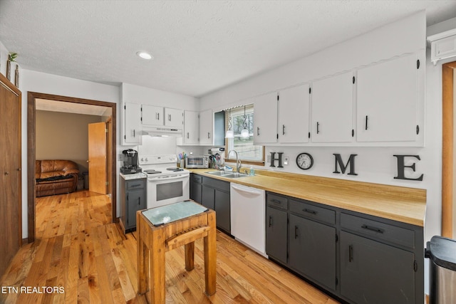 kitchen with white appliances, a sink, white cabinets, and under cabinet range hood