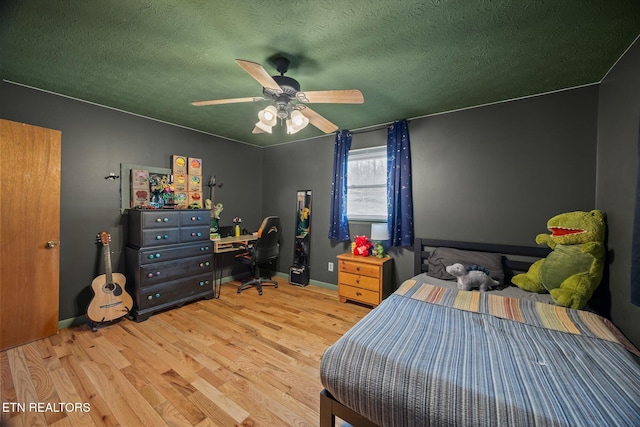 bedroom with baseboards, a textured ceiling, a ceiling fan, and wood finished floors