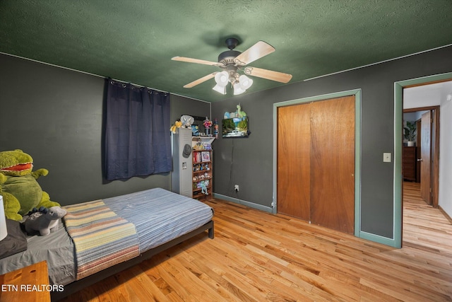 bedroom with a textured ceiling, ceiling fan, wood finished floors, and baseboards