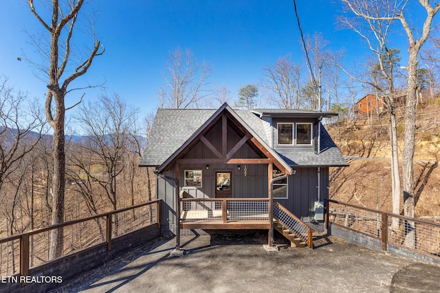 view of front of property featuring board and batten siding, a shingled roof, and fence