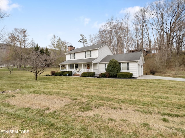 view of front of house with a chimney, covered porch, an attached garage, a front yard, and driveway