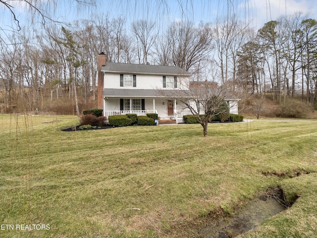 view of front of home with covered porch, a chimney, and a front yard