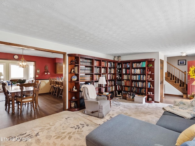 living area with a textured ceiling, stairway, and a notable chandelier