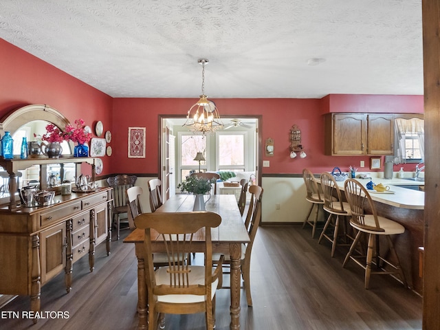 dining area featuring dark wood-type flooring, a chandelier, a textured ceiling, and baseboards