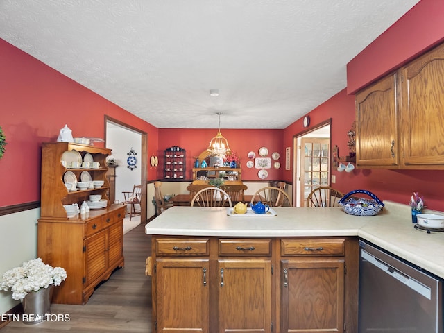 kitchen with light countertops, dishwasher, a peninsula, and wood finished floors