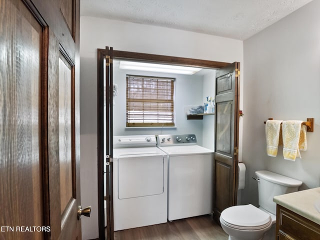 bathroom featuring toilet, wood finished floors, washing machine and clothes dryer, a textured ceiling, and vanity