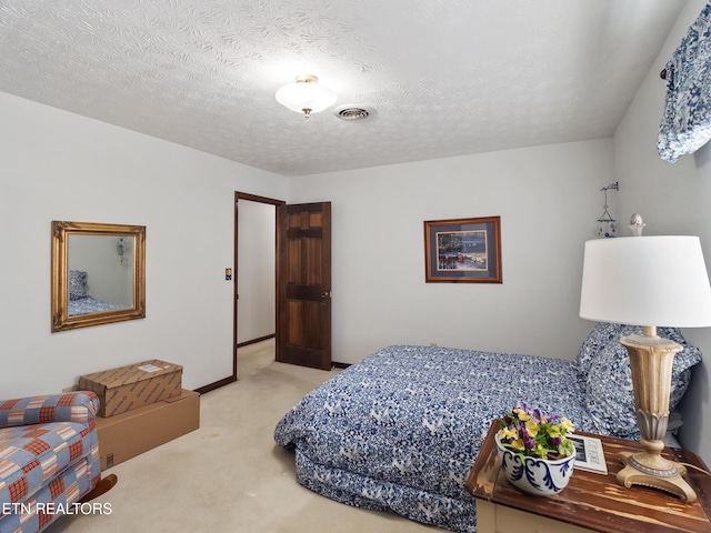 carpeted bedroom featuring a textured ceiling, visible vents, and baseboards