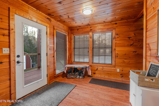 entryway with wood walls, wooden ceiling, and wood finished floors