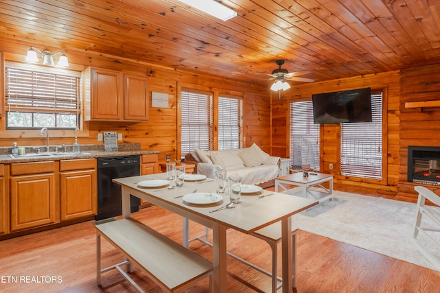 kitchen featuring a sink, open floor plan, black dishwasher, light wood-type flooring, and a large fireplace