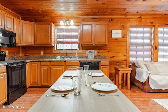 kitchen with wooden walls, a sink, black appliances, wood ceiling, and light wood-type flooring