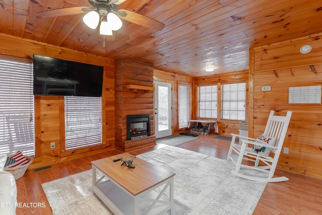 living area featuring visible vents, a multi sided fireplace, wood ceiling, wood finished floors, and rustic walls