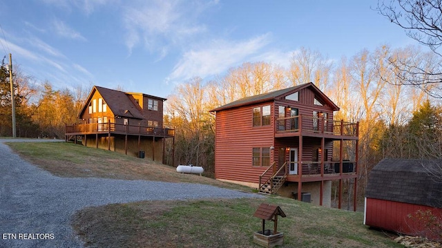 rear view of property featuring an outbuilding, a yard, a shed, and driveway