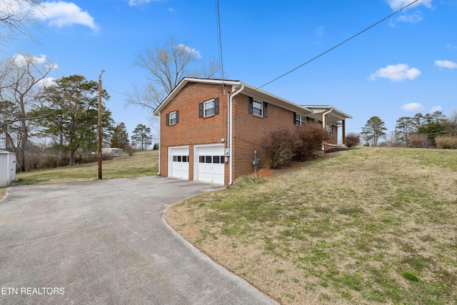 view of home's exterior featuring driveway, a yard, an attached garage, and brick siding