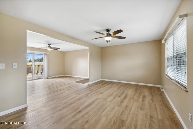 empty room with ceiling fan, plenty of natural light, baseboards, and light wood-style flooring