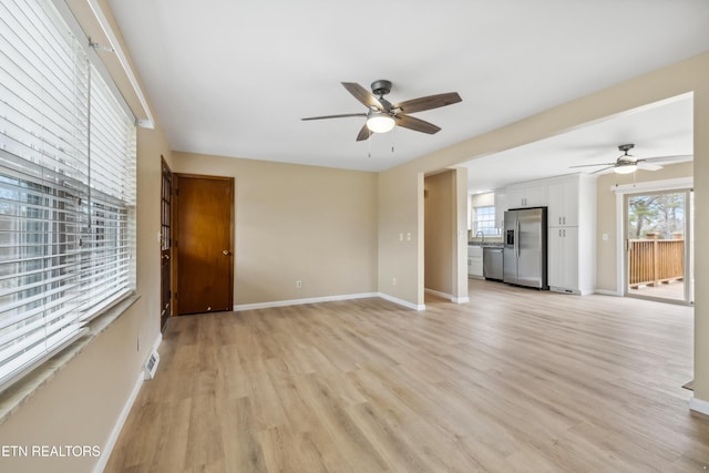 unfurnished living room with baseboards, ceiling fan, and light wood-style floors