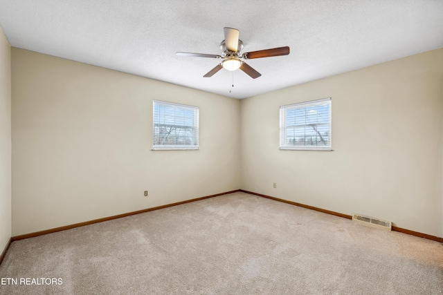 spare room featuring baseboards, visible vents, ceiling fan, a textured ceiling, and carpet floors