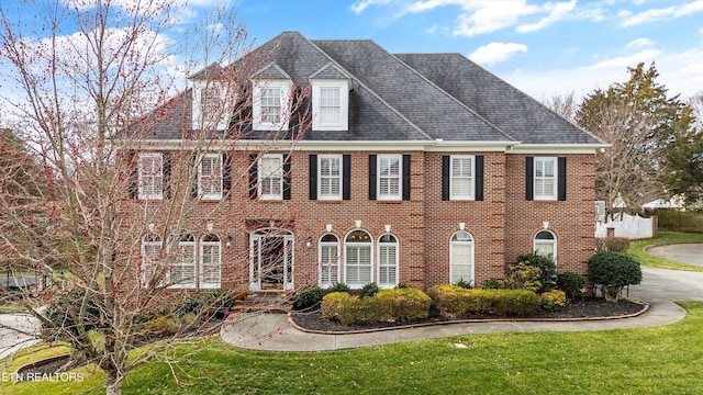 georgian-style home featuring brick siding and a front lawn