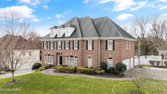 colonial-style house with fence, concrete driveway, a front yard, a garage, and brick siding