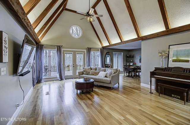 living room with baseboards, light wood finished floors, high vaulted ceiling, french doors, and beamed ceiling