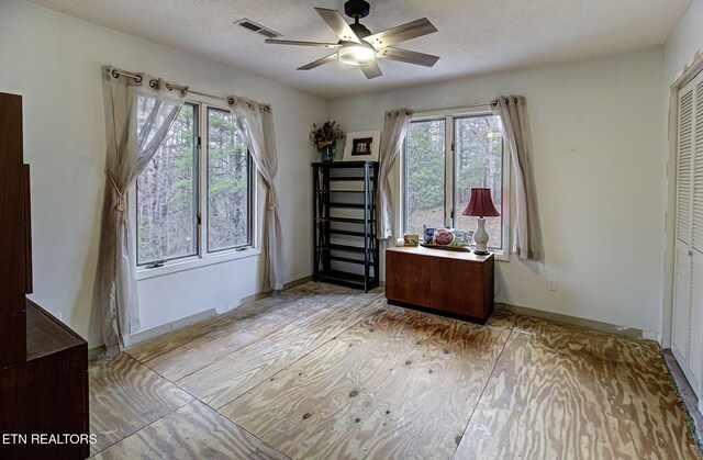 unfurnished bedroom with light wood-style flooring, multiple windows, visible vents, and a textured ceiling